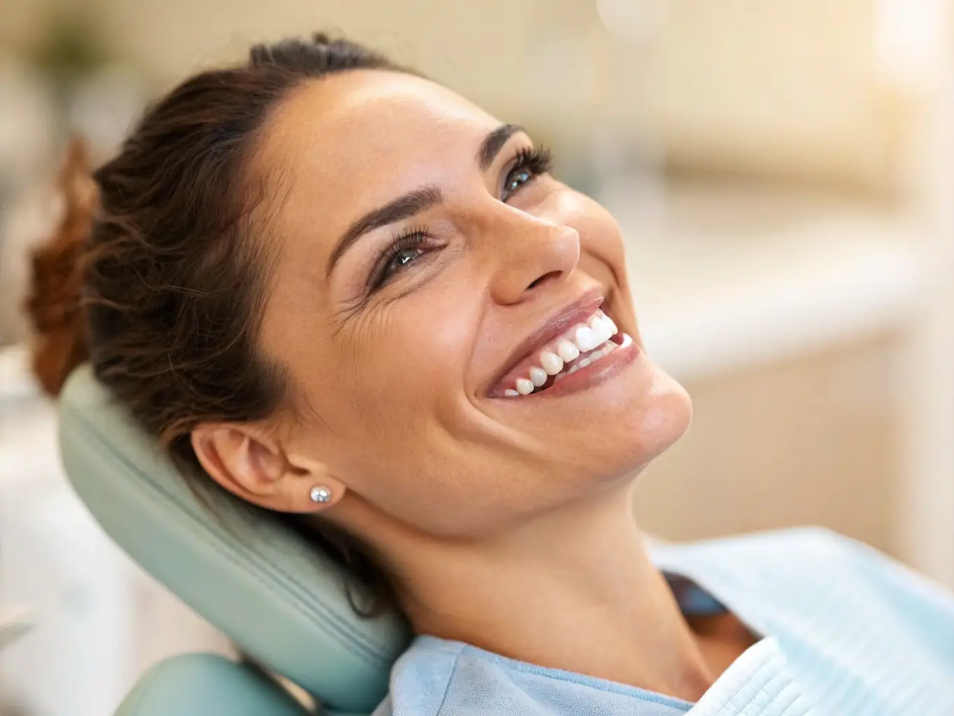 An adult is smiling broadly, showcasing improved oral hygiene and comfort after undergoing a laser frenectomy to address gum recession and spacing issues.